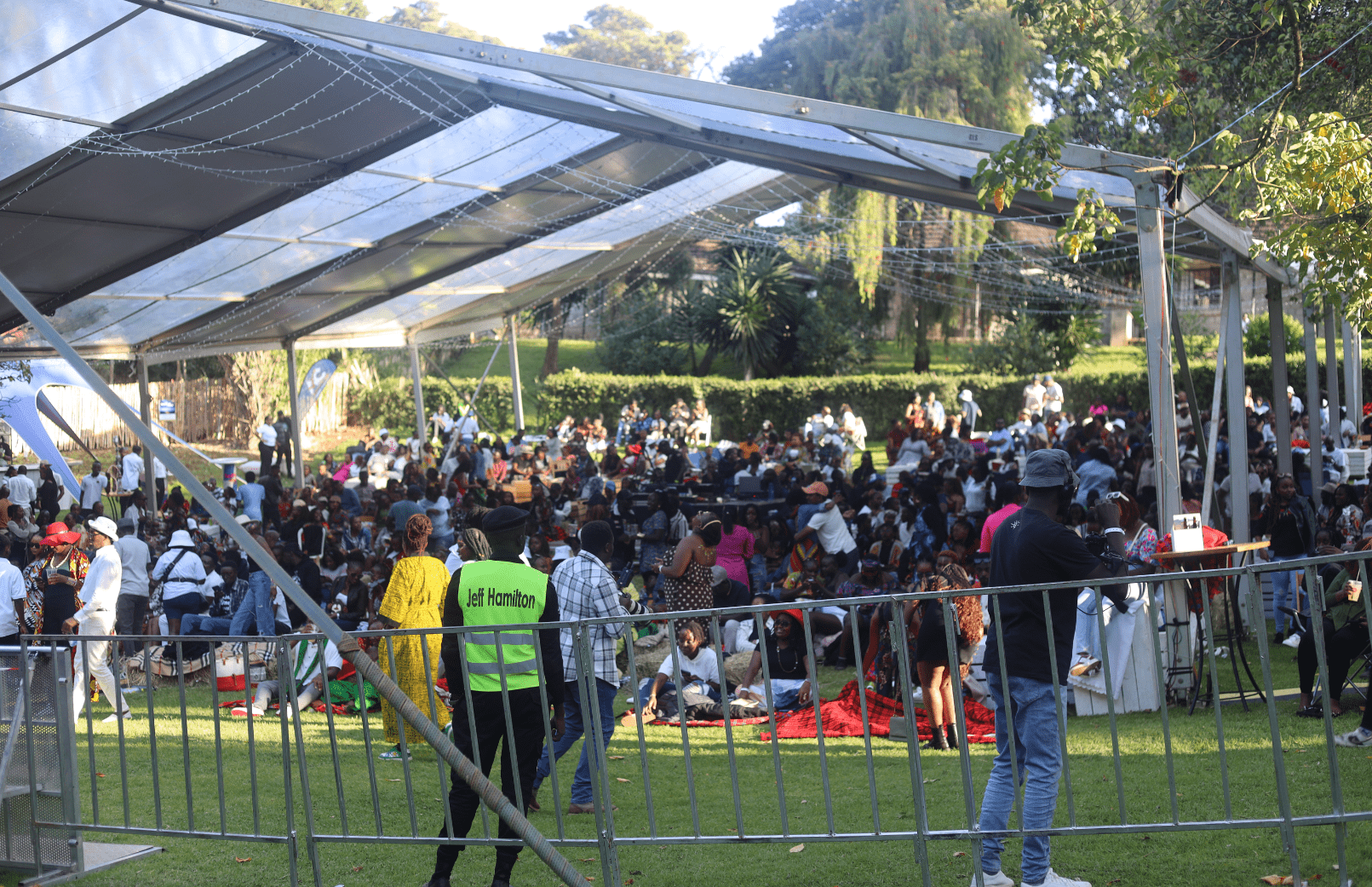 Wide shot of a crowd at an outdoor festival under a large tent